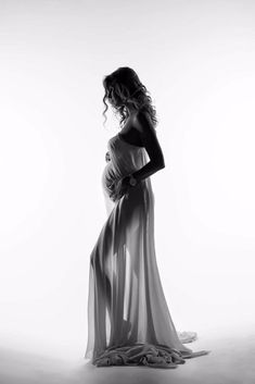 black and white photo of pregnant woman in evening gown standing with her back turned to the camera