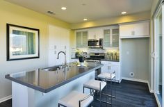 a kitchen with white cabinets and stainless steel counter tops, along with bar stools