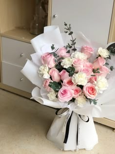 a bouquet of pink and white flowers sitting on top of a counter next to a mirror