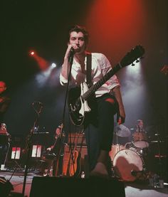 a man holding a guitar while standing on stage