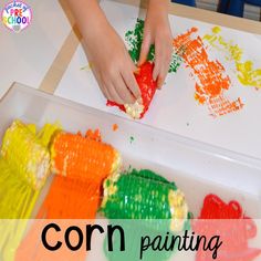 a child's hands painting with crayons on a paper plate in the shape of fish