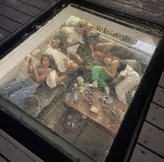 the reflection of people sitting on couches in a glass table with wood planks