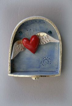 a red heart in a blue box with angel wings