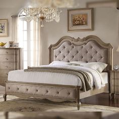 a bedroom with a bed, dresser and chandelier