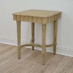 a small wooden table sitting on top of a hard wood floor next to a white wall