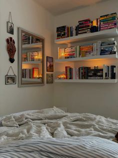 a bedroom with bookshelves above the bed and two pictures on the wall behind it