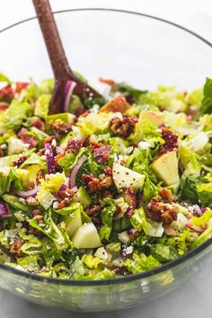 a salad in a glass bowl with a wooden spoon