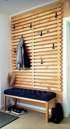 a wooden bench sitting in front of a wall with shoes on the floor and coat rack