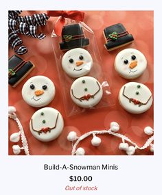 decorated cookies in the shape of snowmen on a red table with candy and decorations