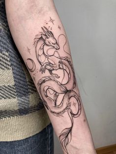 a woman's arm with a dragon tattoo on the left side of her arm