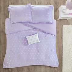 a bed with purple and white polka dots on it, next to a night stand