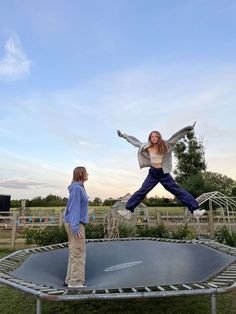 two people standing on top of a trampoline in the middle of a field