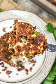 a white plate topped with food on top of a green leafy table next to a knife