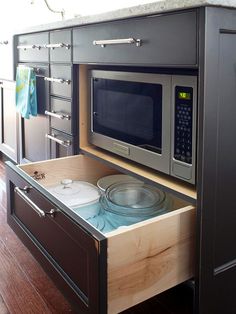 an open drawer in the middle of a kitchen with a microwave and dishwasher