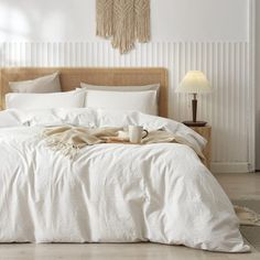 a bed with white sheets and pillows in a room