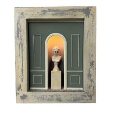 a small statue in a wooden frame with an arch on the side and a door to another room behind it