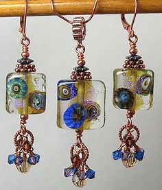 three square glass beads hanging from a wooden rod with copper earwires and bead hooks