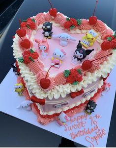 a heart shaped birthday cake decorated with cartoon characters