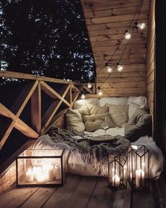 a bed sitting on top of a wooden floor next to a light filled room with candles