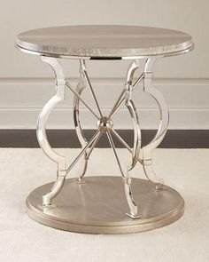 a round table with metal legs and a glass top on a white carpeted floor