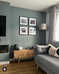 a living room with gray walls and pictures on the wall above the couch, along with a television