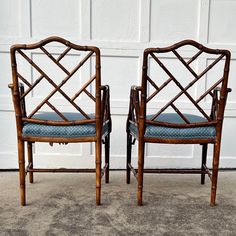 pair of bamboo chairs with blue upholstered seat cushions in front of a garage door