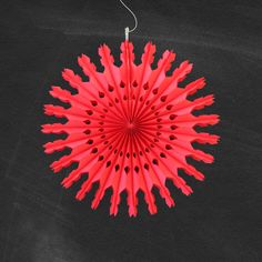 a red paper fan hanging from a string on a black background with space for text