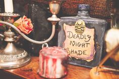 some candles are sitting on a table next to a bottle and candle holder with a sign that says deadly night shade