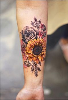 a sunflower and rose tattoo on the left leg, with other flowers around it