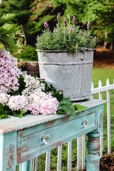 a potted plant sitting on top of a wooden table next to a white picket fence