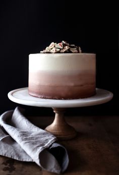 a chocolate cake with white frosting and sprinkles sitting on a plate