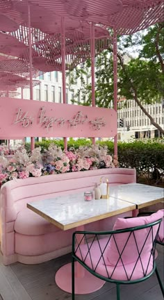 a pink couch sitting under a canopy next to tables with chairs and flowers on it