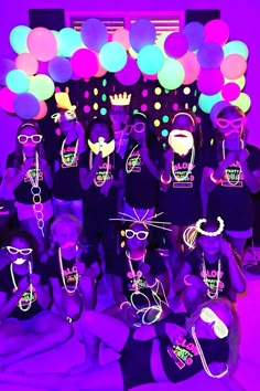 a group of people in black shirts and neon glasses posing for a photo with balloons