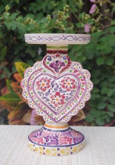 a decorative vase sitting on top of a table next to some plants and flowers in the background