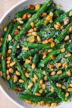 a white bowl filled with green beans and parmesan sprinkled on top