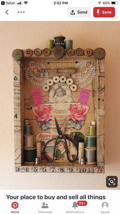 an altered photograph with scissors, thread and buttons in a wooden box on the wall