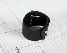 This black leather cuff strikes the perfect balance between casual and dressy. It's the perfect accent piece, and is also fully adjustable, making it an ideal treat for yourself or a gift for someone special.Soft cowhide leather with suede lining.  Adjustable sizing, features metal post closures. Fits wrists from 14cm to 18cm. Black leather, suede lining color may vary.Available in a variety of other colours: https://www.etsy.com/shop/Rimanchik/search?search_query=flare&order=date_desc&v Casual Black Adjustable Cuff Bracelet, Casual Adjustable Black Cuff Bracelet, Adjustable Edgy Cuff Bracelet, Edgy Leather Cuff Bracelet, Black Cuff Bracelet As Gift, Edgy Adjustable Leather Bracelet As Gift, Black Cuff Bracelet Gift, Edgy Adjustable Cuff Leather Bracelet, Edgy Adjustable Leather Bracelet For Gifts