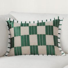 a green and white checkered pillow sitting on top of a couch