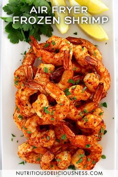 air fryer frozen shrimp on a white plate with lemon wedges and parsley