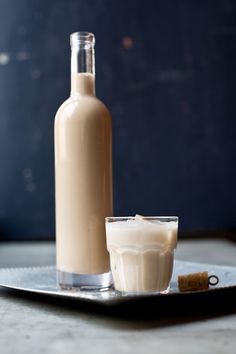 a bottle of milk and a glass on a plate with a corkscrew next to it