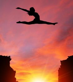 the silhouette of a person jumping off rocks into the air at sunset or dawn,