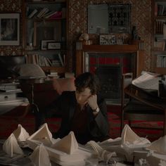 a woman sitting at a table covered in folded paper