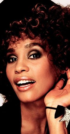 a close up of a person with curly hair wearing a black shirt and bracelets