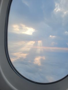 the view from an airplane window looking out at clouds and sun shining down on them