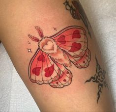 a red and white butterfly tattoo on the thigh, with hearts in it's wings