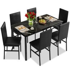 a black dining table with four chairs around it and plates of food on the table