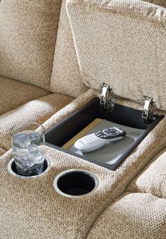 a remote control sitting on top of a couch next to a cup and glass filled with water