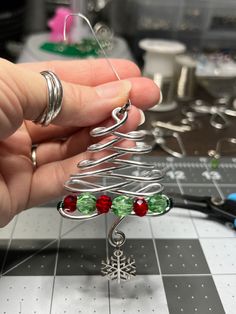 a person holding a wire christmas tree ornament on top of a piece of metal