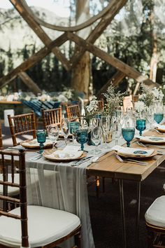 the table is set with blue and white plates, silverware, napkins, and candles