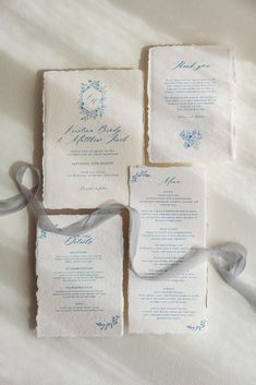 the wedding stationery is laid out on top of each other with ribbons tied around them